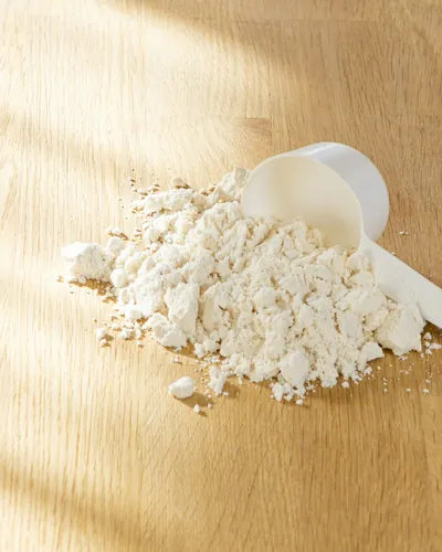 Proteinpulver og måleske på et træbord